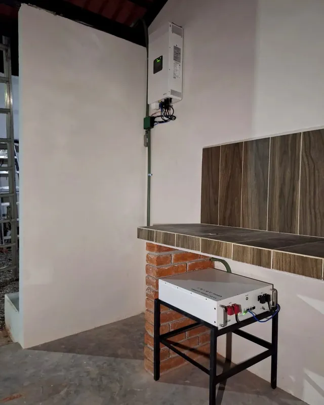 Inversor en muro y batería sobre una base metálica junto a una barra