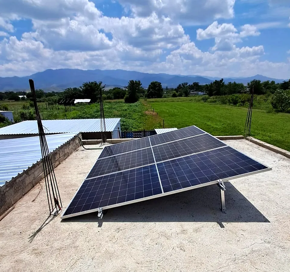 Paneles solares del sistema aislado sobre una azotea, con campo y cerros al fondo