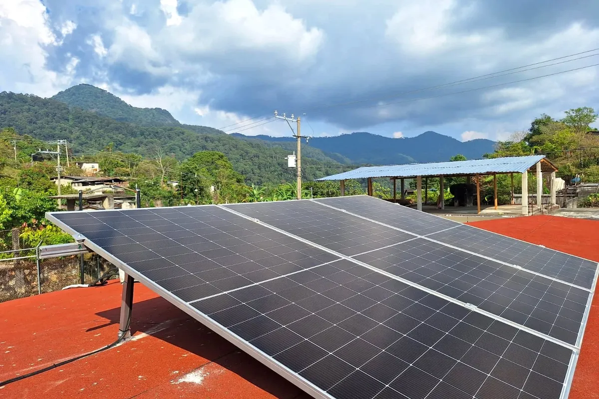 Paneles solares sobre una azotea roja con montañas al fondo