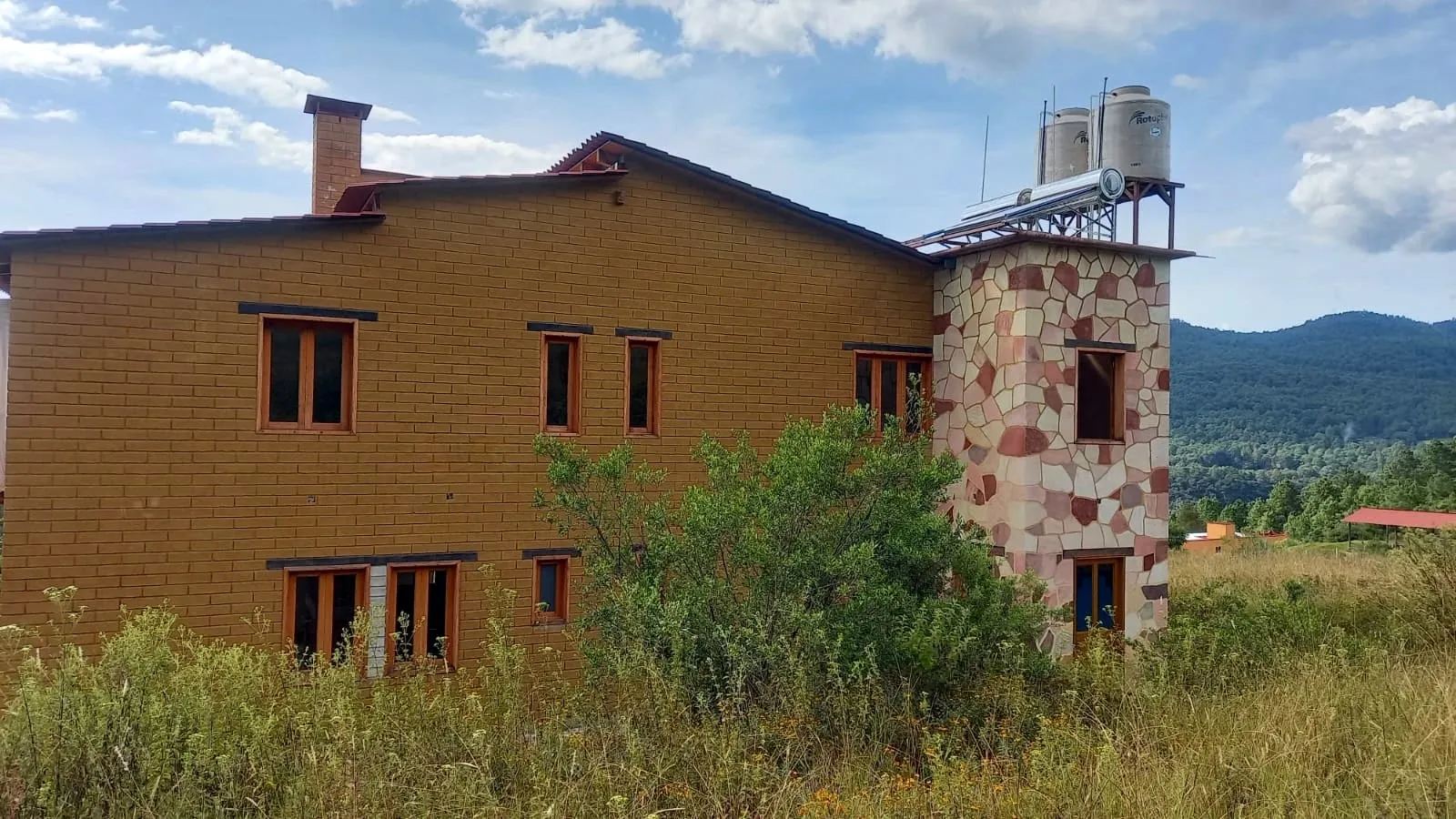 Casa de ladrillo con calentador solar instalado en la torre de los tinacos