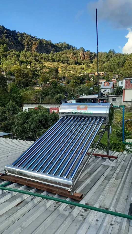 Calentador solar sobre techo de lámina con casas y cerros al fondo