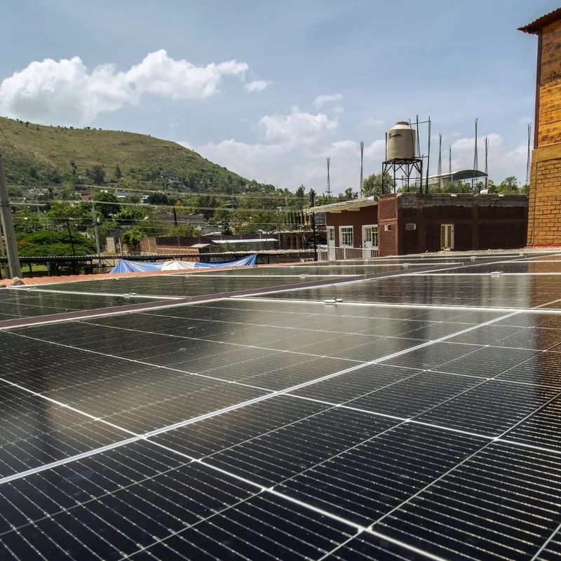 Paneles solares en azotea junto a un edificio de madera y ladrillo